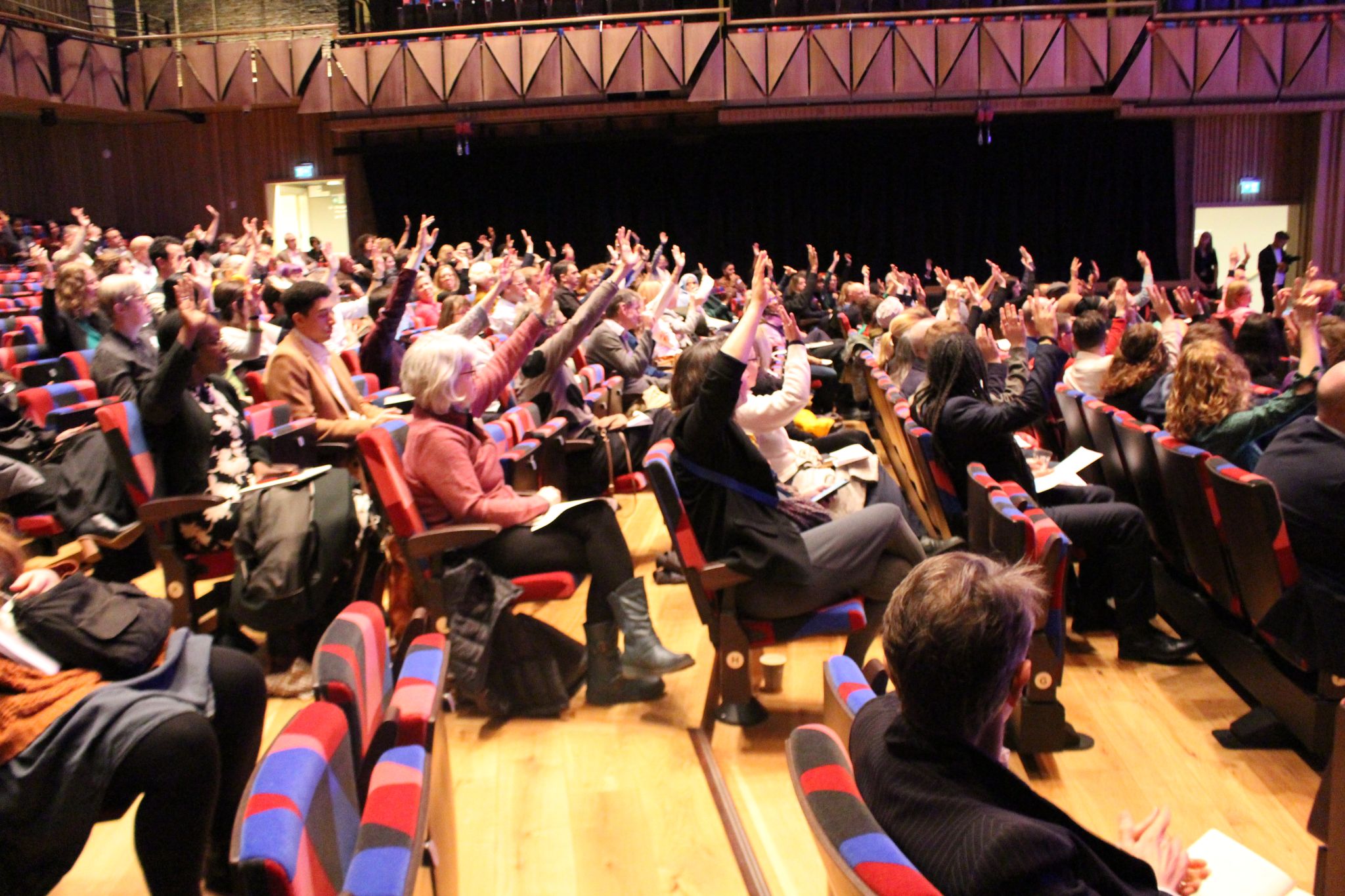 Picture of the March 2024 City Gathering crowd at the Bristol Beacon, some of the crowd have their arms raised.